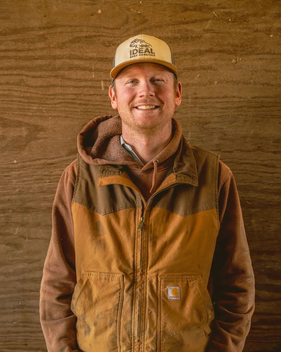 rancher standing outdoors wearing brown jacket and hat