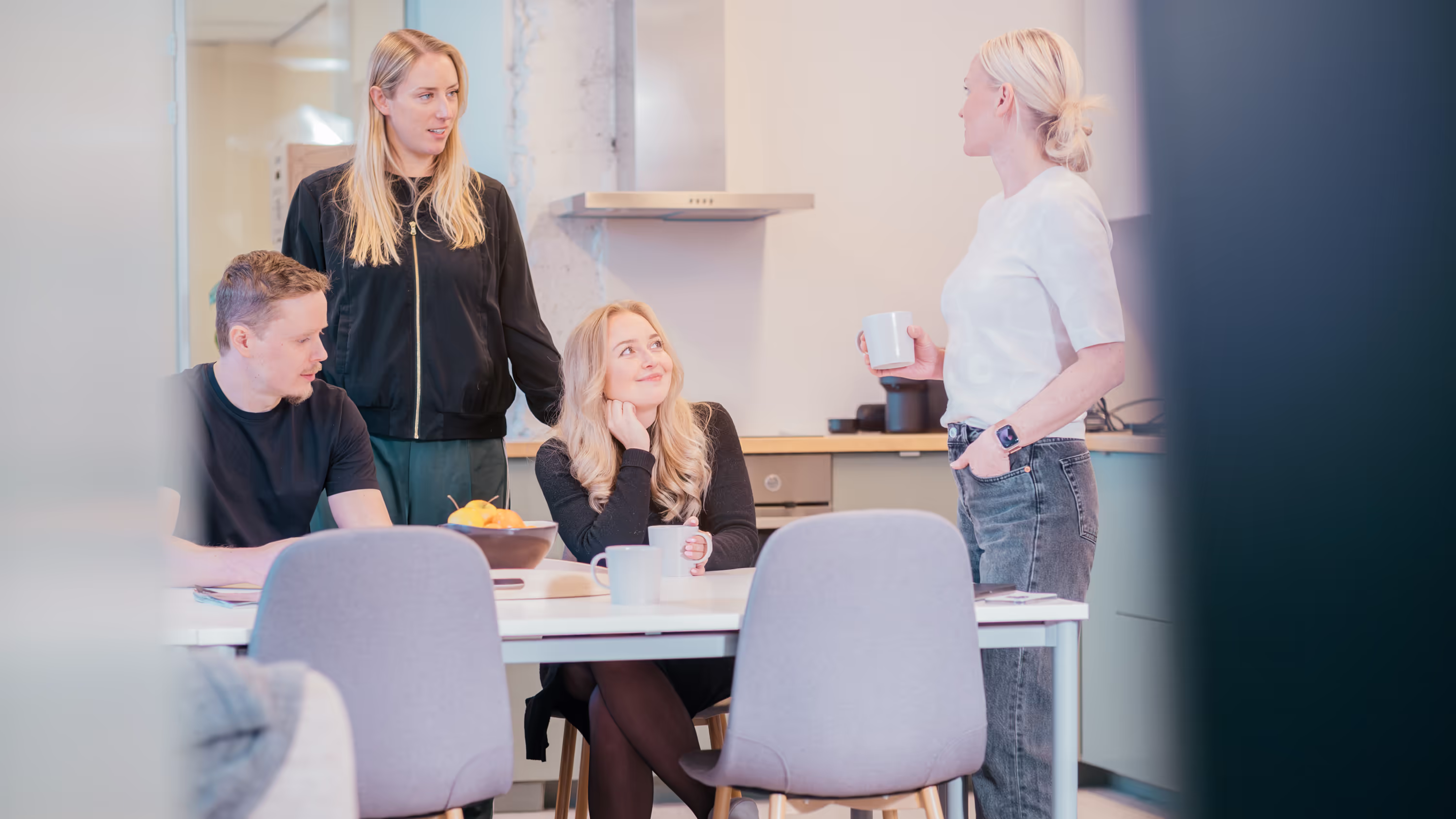 Four people chatting in a kitchen.