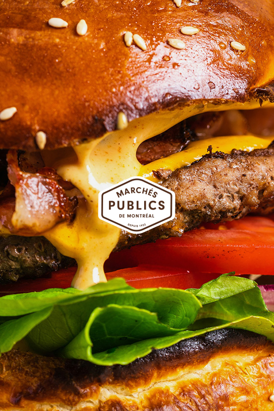 Close-up image of a burger with the Marchés Publics de Montréal's logo in the middle.