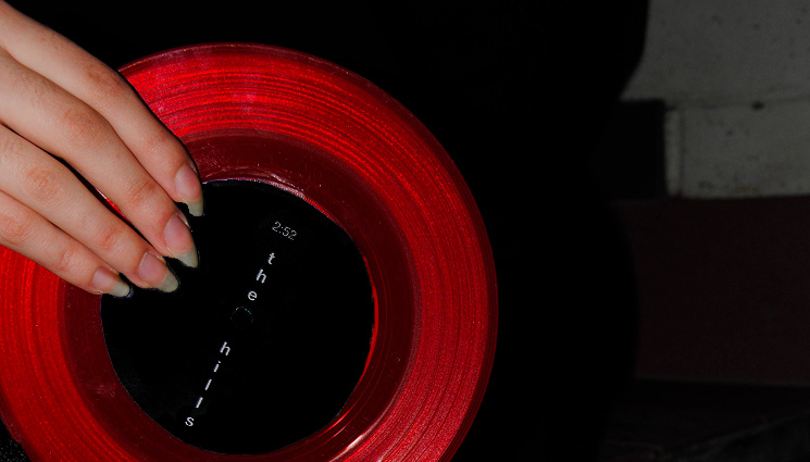 Image of someone holding the Néo-Romance vinyl adaptation's red vinyl.