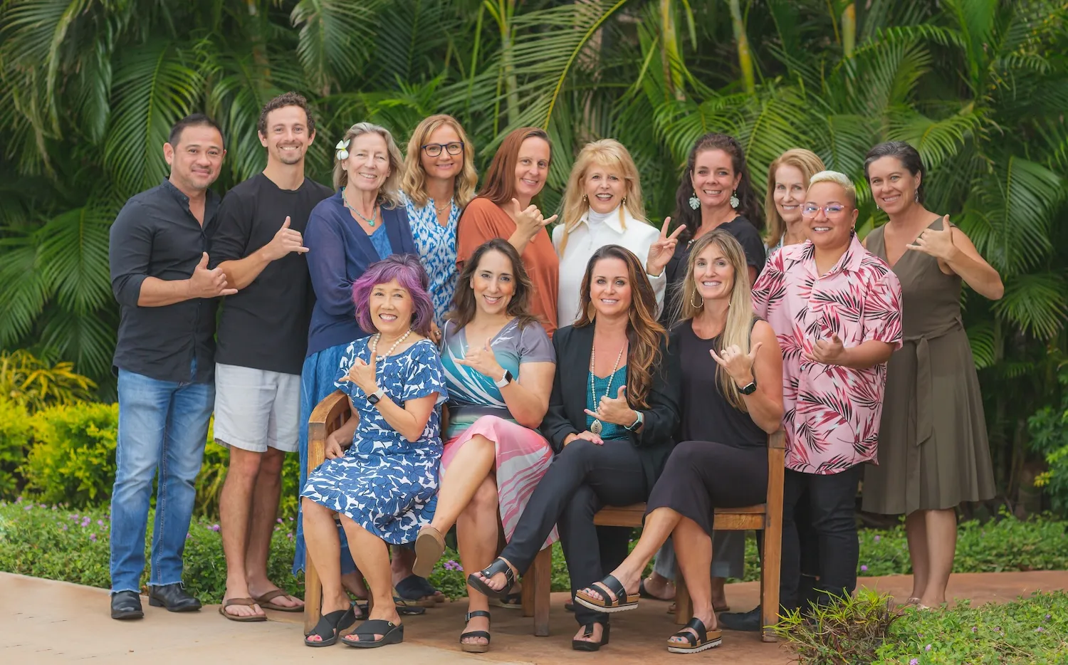 Group of diverse people smiling at camera in front of green tropical foliage background