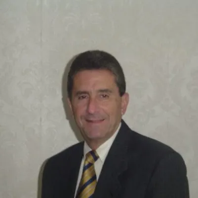 Portrait of a middle-aged man wearing a dark suit and yellow striped tie, smiling against a light patterned background.