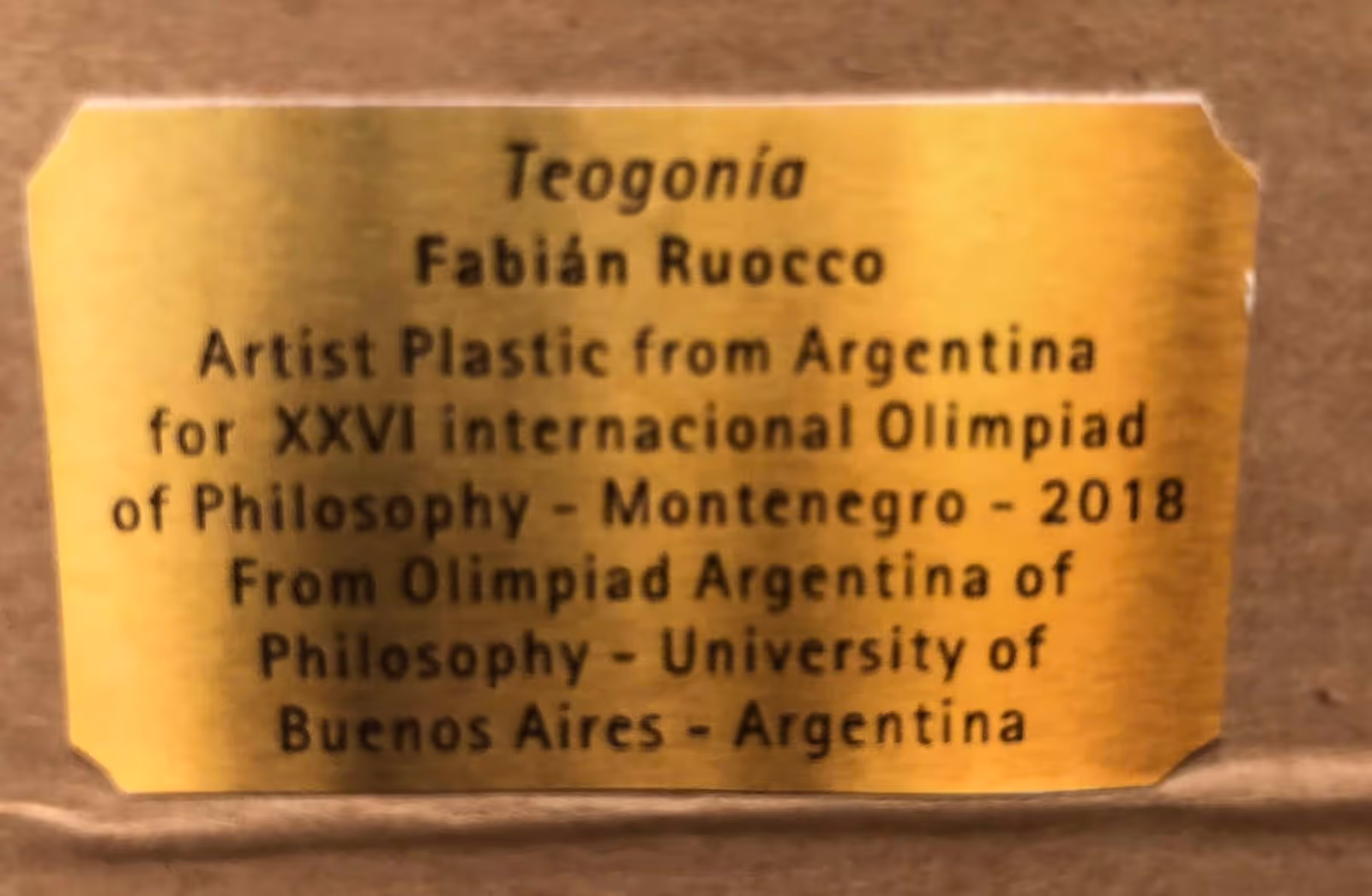 Niños sentados en sillas blancas escuchando una charla en una galería de arte con pinturas abstractas en las paredes.