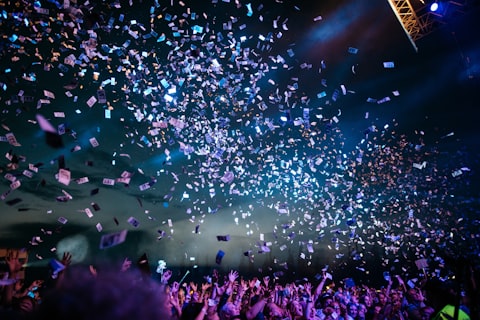 Confettis tombant sur une foule en liesse lors d'un concert ou événement festif en soirée.