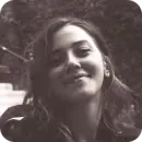 Young woman with long hair smiling gently at the camera in a monochrome photograph.