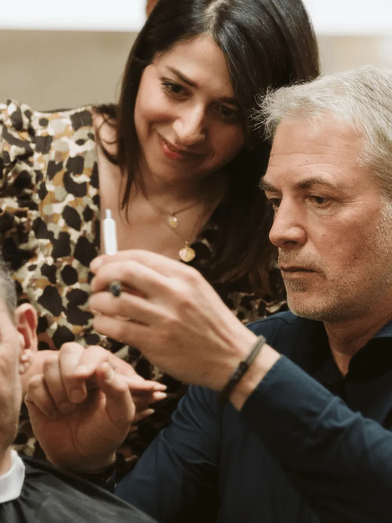 Friseur konzentriert sich aufs Haareschneiden, während Frau zusieht.
