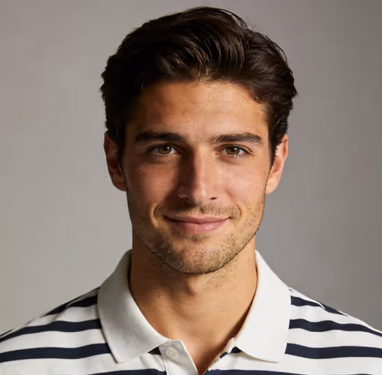 Smiling young man with dark hair wearing a white polo shirt with black horizontal stripes against a plain gray background.