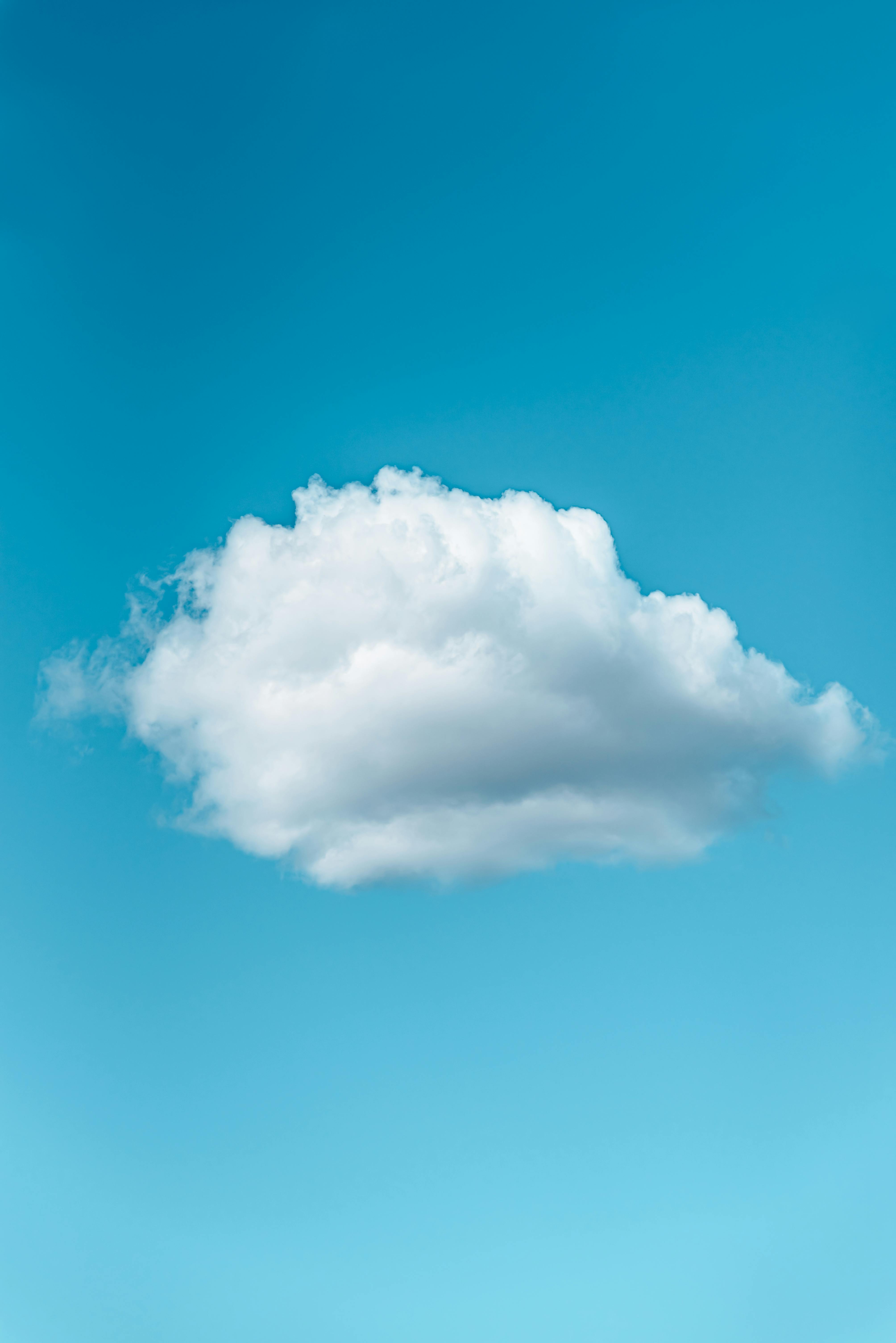 A single fluffy white cloud floating in a clear blue sky.