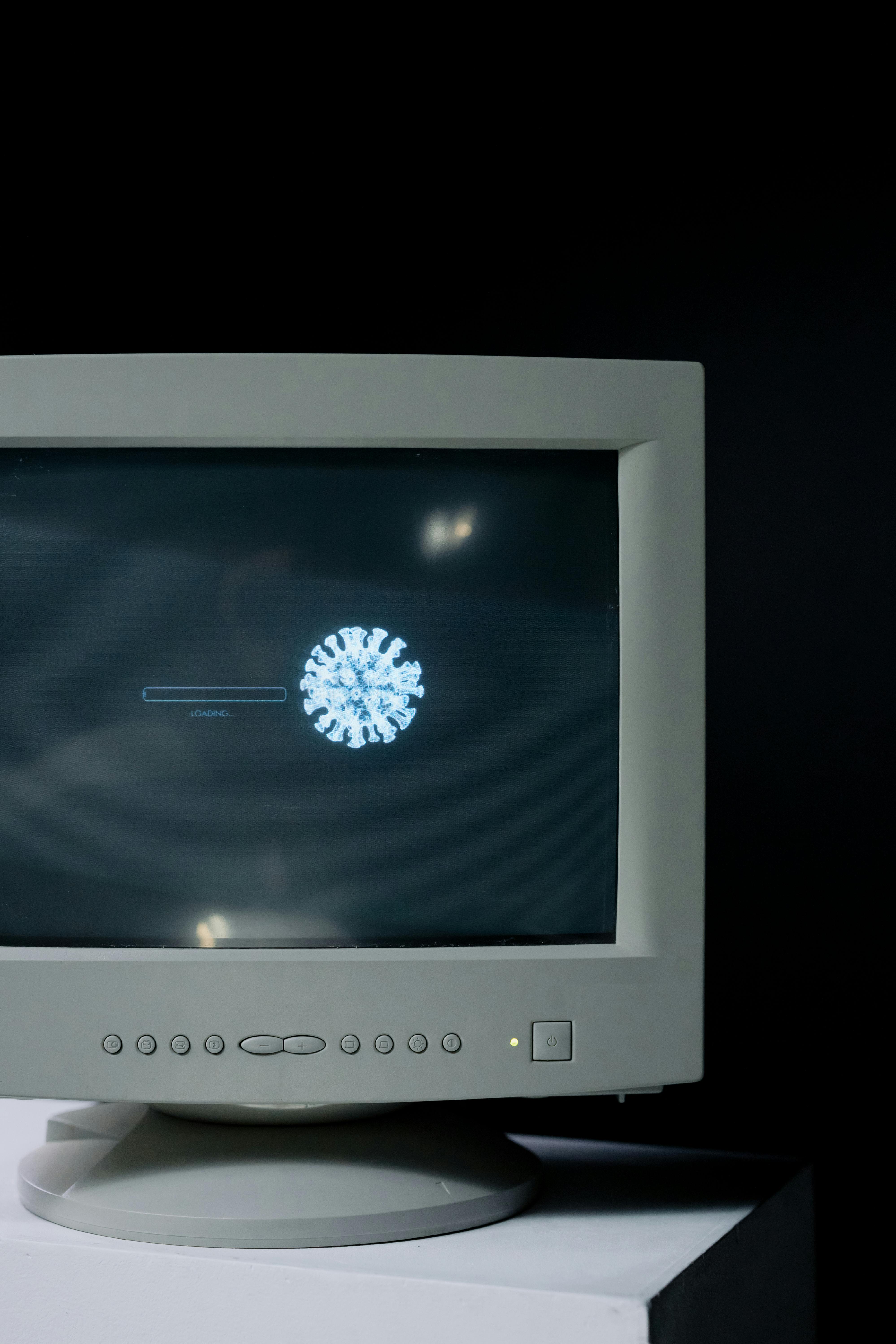 Old computer monitor showing a loading bar with a virus icon on the screen.