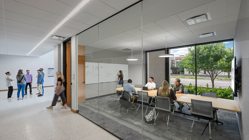 Conference room with people walking in hallway