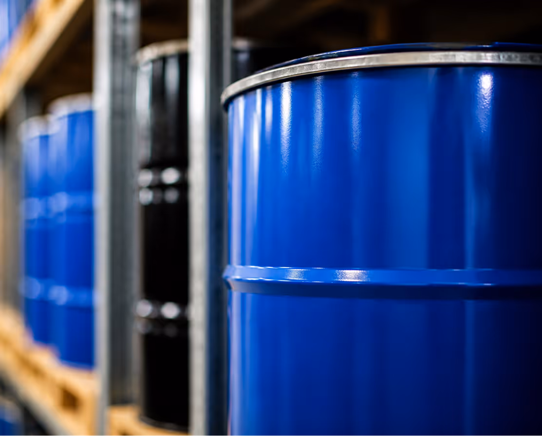 Close-up of blue and black industrial barrels on warehouse metal shelving.