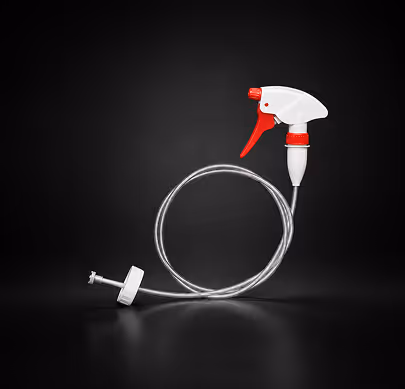 White and red spray bottle trigger with attached long clear tube on black background.