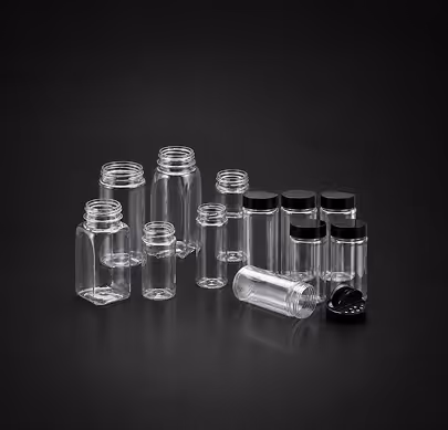 Clear empty plastic jars with black lids, some open and some closed, arranged on black background.