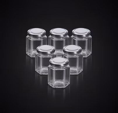 Six empty hexagonal glass jars with silver lids arranged on a black background.