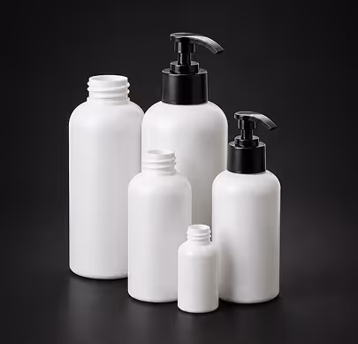 Group of five white cosmetic bottles with black pump and open caps on black background.