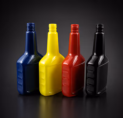 Four empty plastic bottles in blue, yellow, red, and black on a black reflective surface.