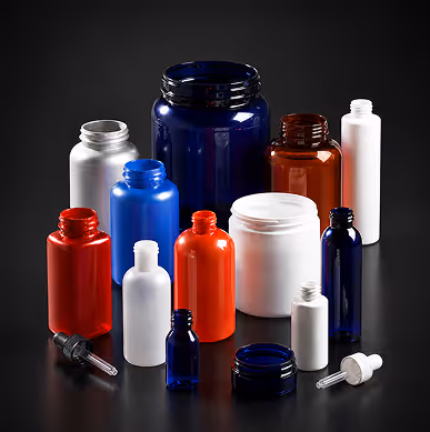 Various empty plastic and glass containers and bottles of different shapes and colors on a black surface.