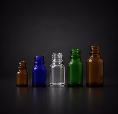 Five empty glass bottles in brown, blue, clear, green, and brown arranged by size on black background.