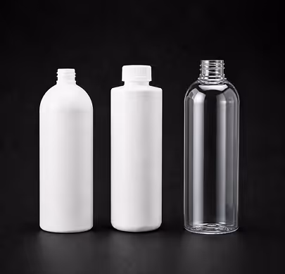 Three empty cosmetic bottles in white and clear plastic on black background.