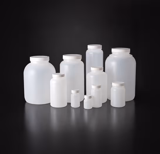 Various sizes of empty white plastic jars with lids on a reflective black surface.