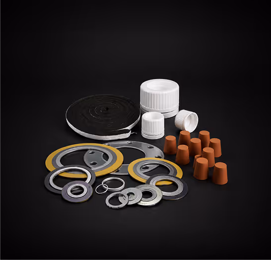 Various industrial gaskets, washers, O-rings, rubber seals, and white plastic caps on black background.