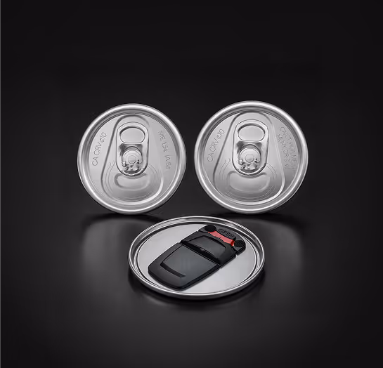 Two silver can tops with a black car key on a silver plate against a black background.