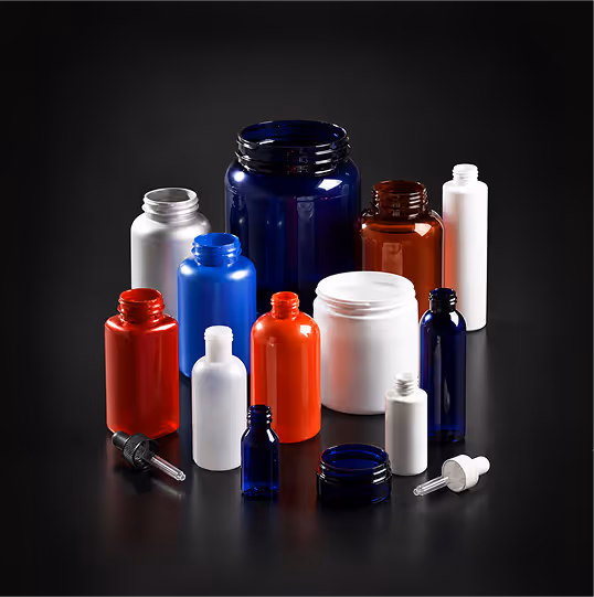 Variety of empty plastic and glass bottles and jars in different colors on a black surface.