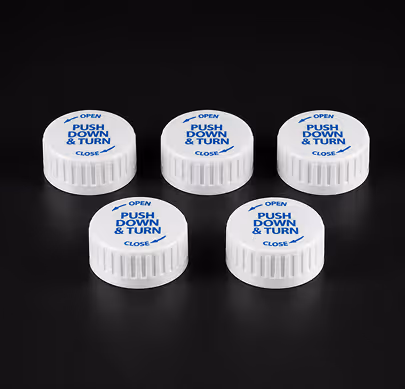 Five white child-resistant bottle caps with blue text reading 'Push Down & Turn' on black surface.