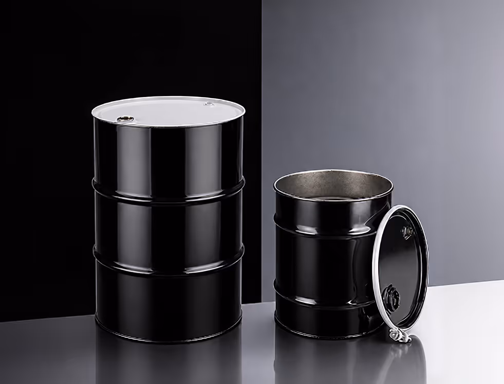 Two black metal barrels on a reflective surface, one closed and one open with its lid beside it.