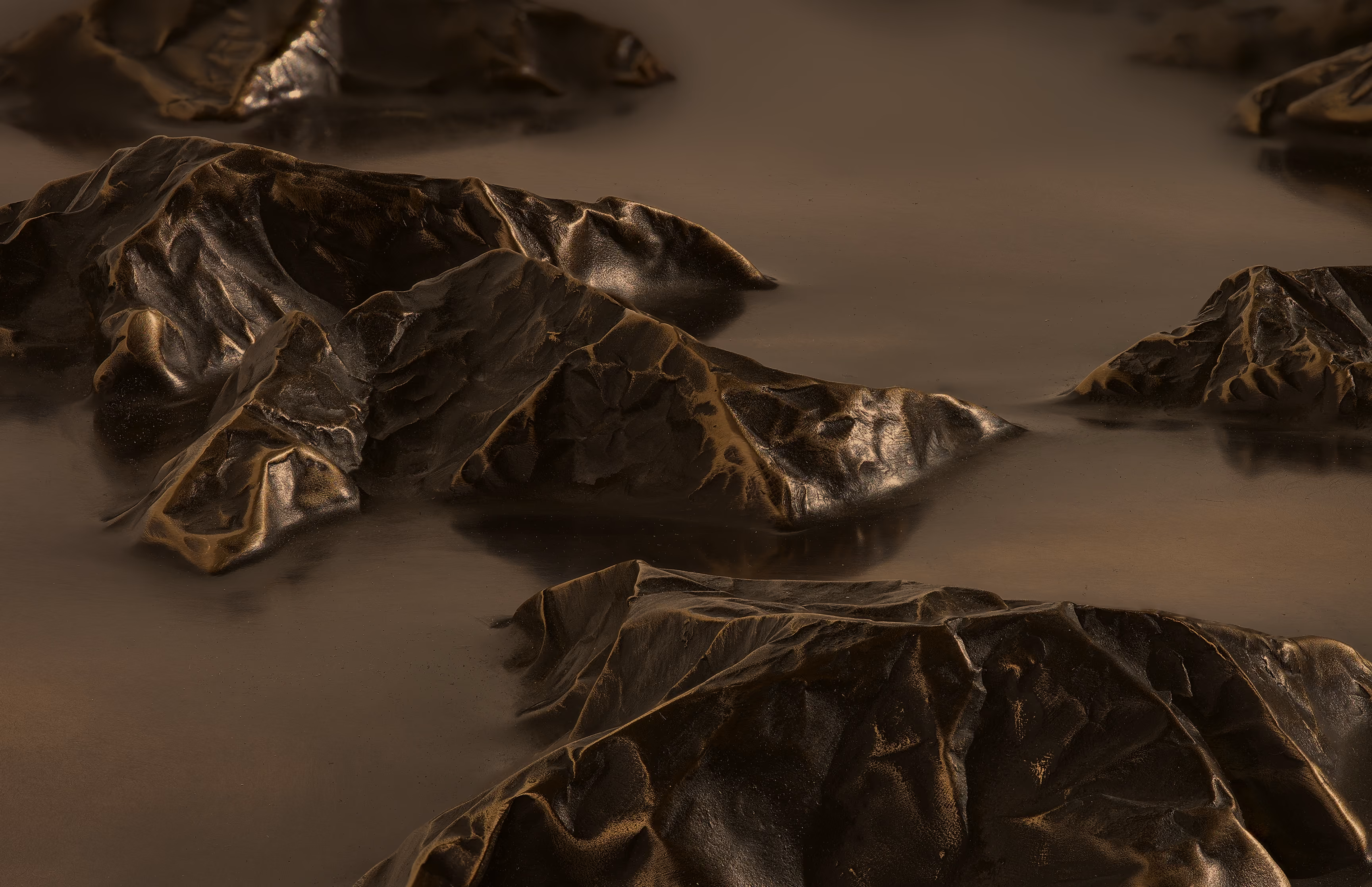Close-up of irregular dark metallic formations with smooth reflective surfaces against a blurred neutral background.