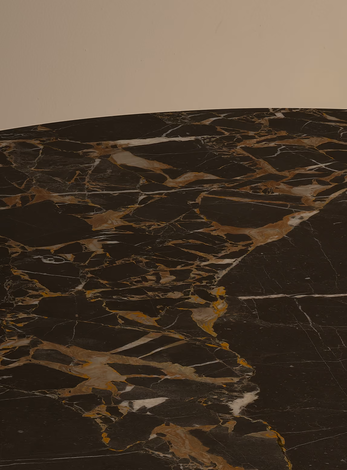 Close-up of a polished black marble tabletop with brown, white, and gold veining patterns.