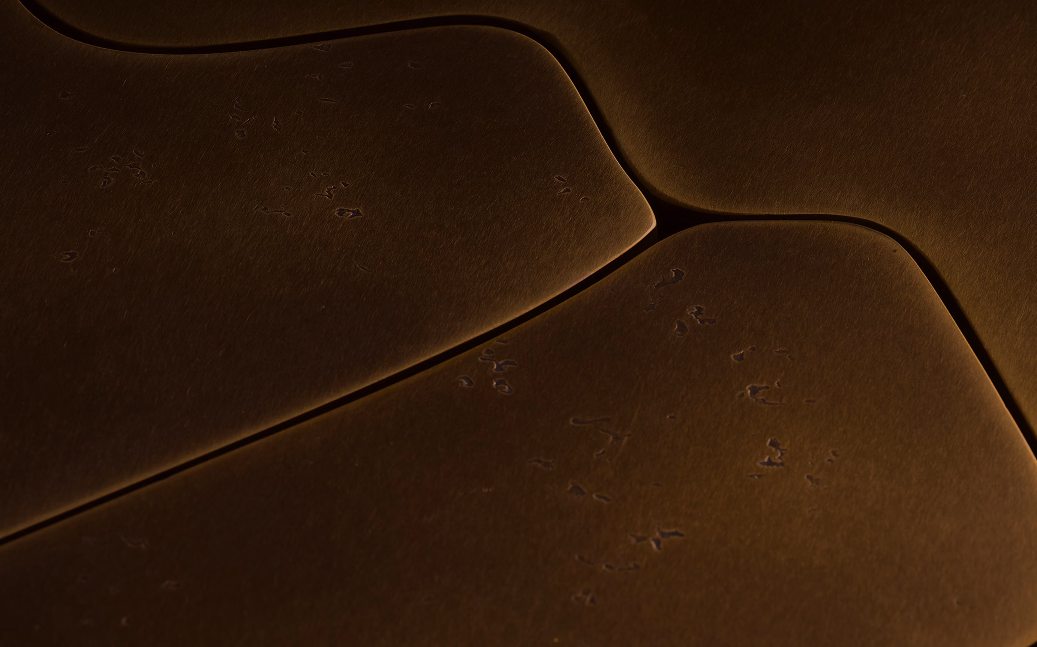 Close-up of dark brown overlapping leather surfaces with visible texture and embossed markings.