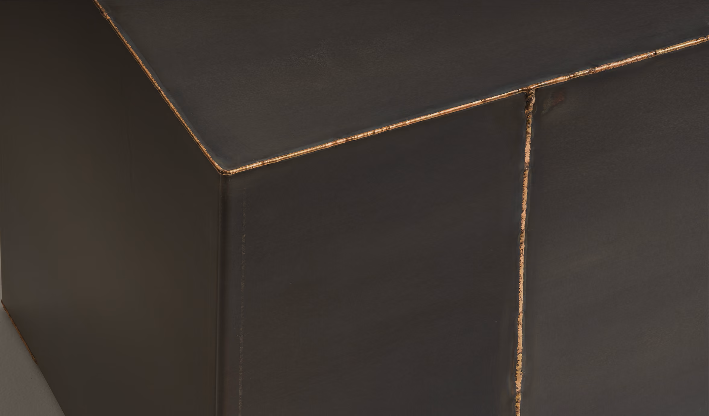 Close-up of stitched black leather with visible seams and slight wear on the edge.