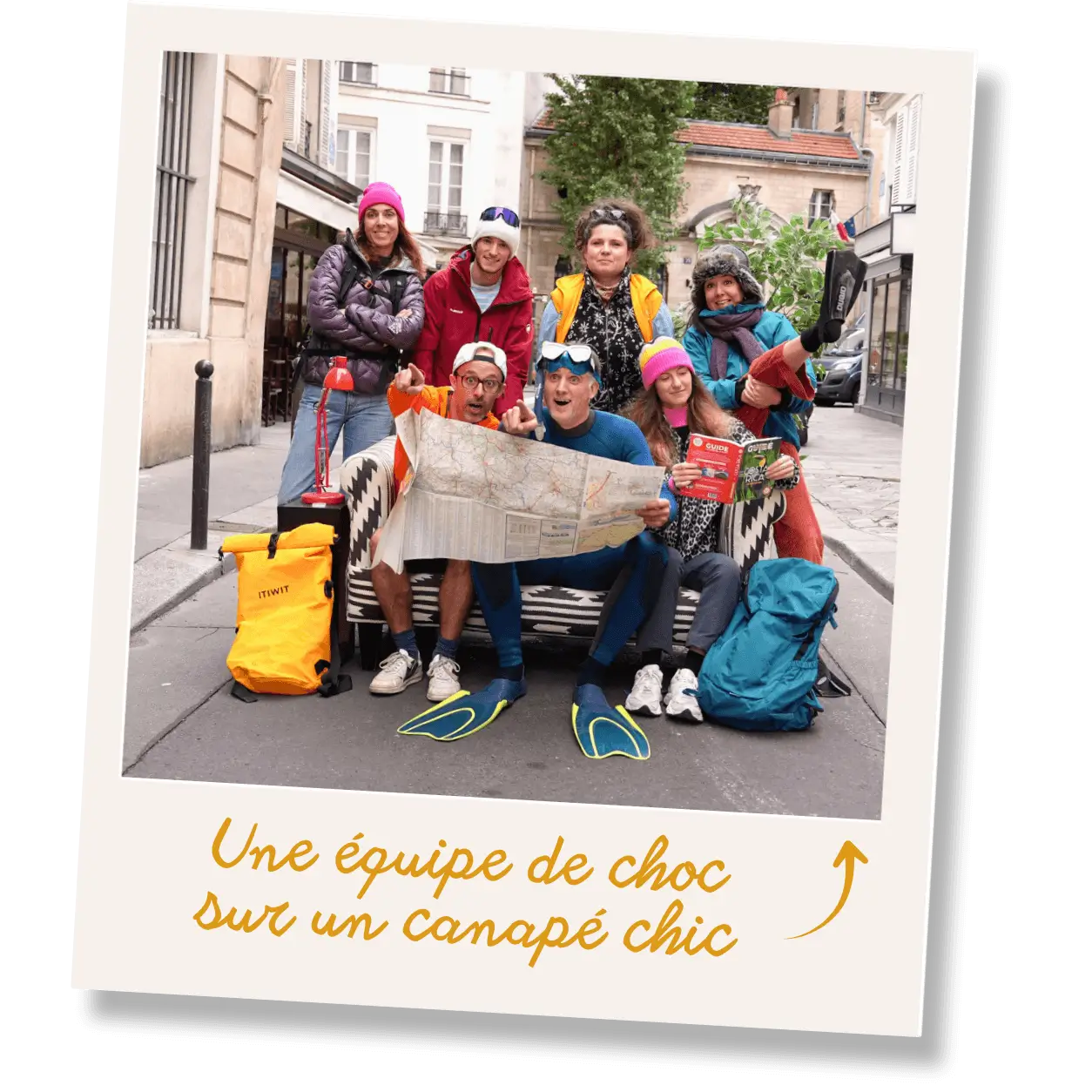 L'équipe de sept personnes habillées en équipement d'aventure posant sur un canapé dans la rue.