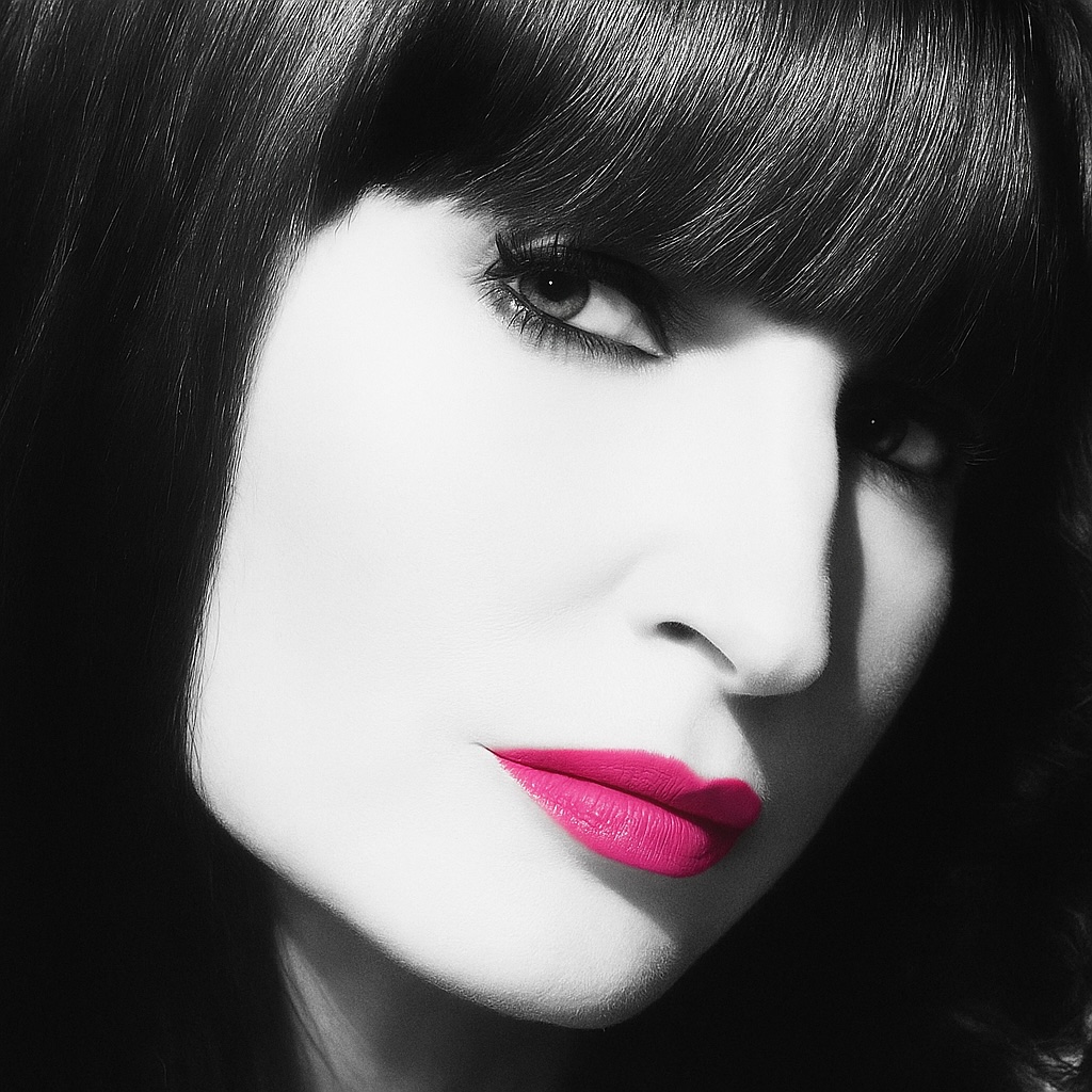 Portrait of Laura Barski, Black and white close-up of a woman with dark hair, prominent eyes, and bright pink lips.