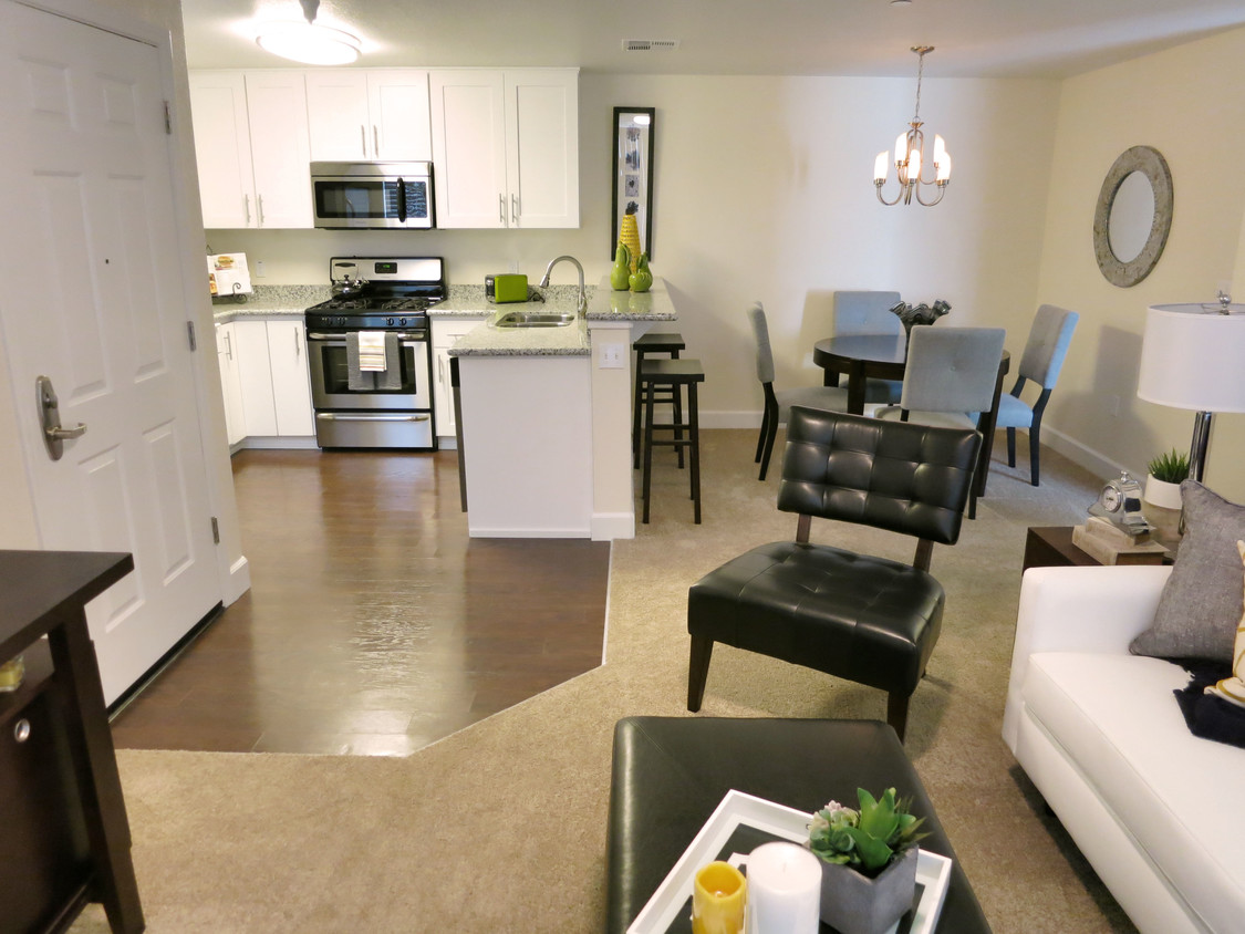 Living area with sofa, chairs, and coffee table, with view into dining area and kitchen