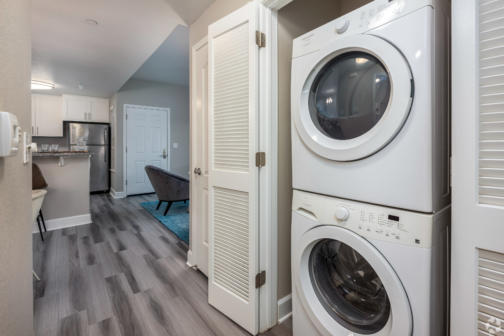 Laundry closet with stacked white appliances
