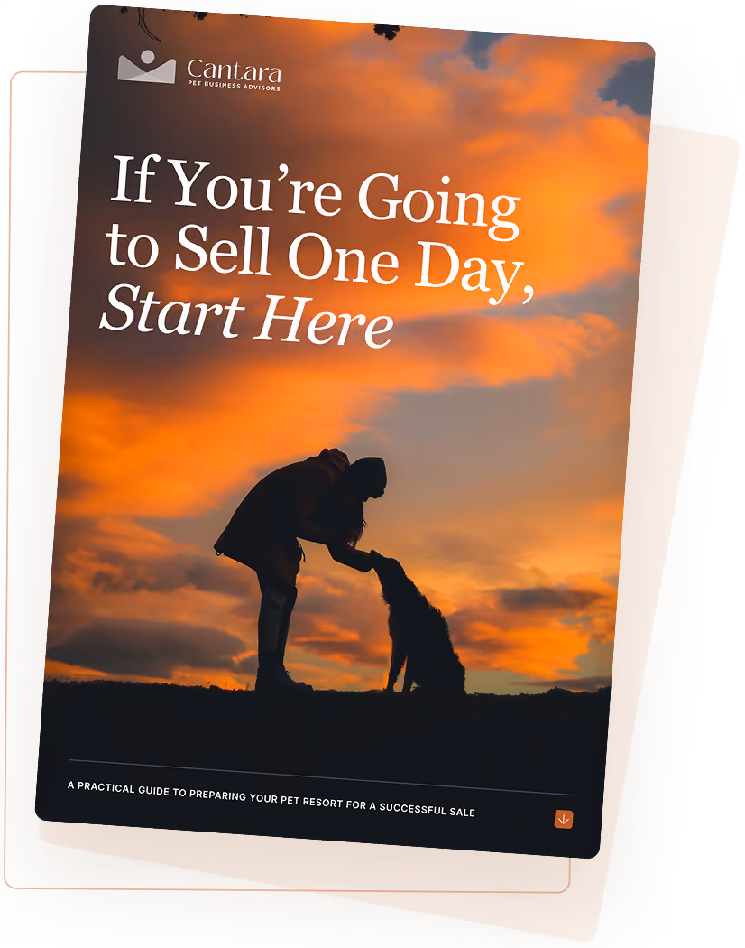 Silhouette of person bending to pet a dog at sunset with orange cloudy sky background.