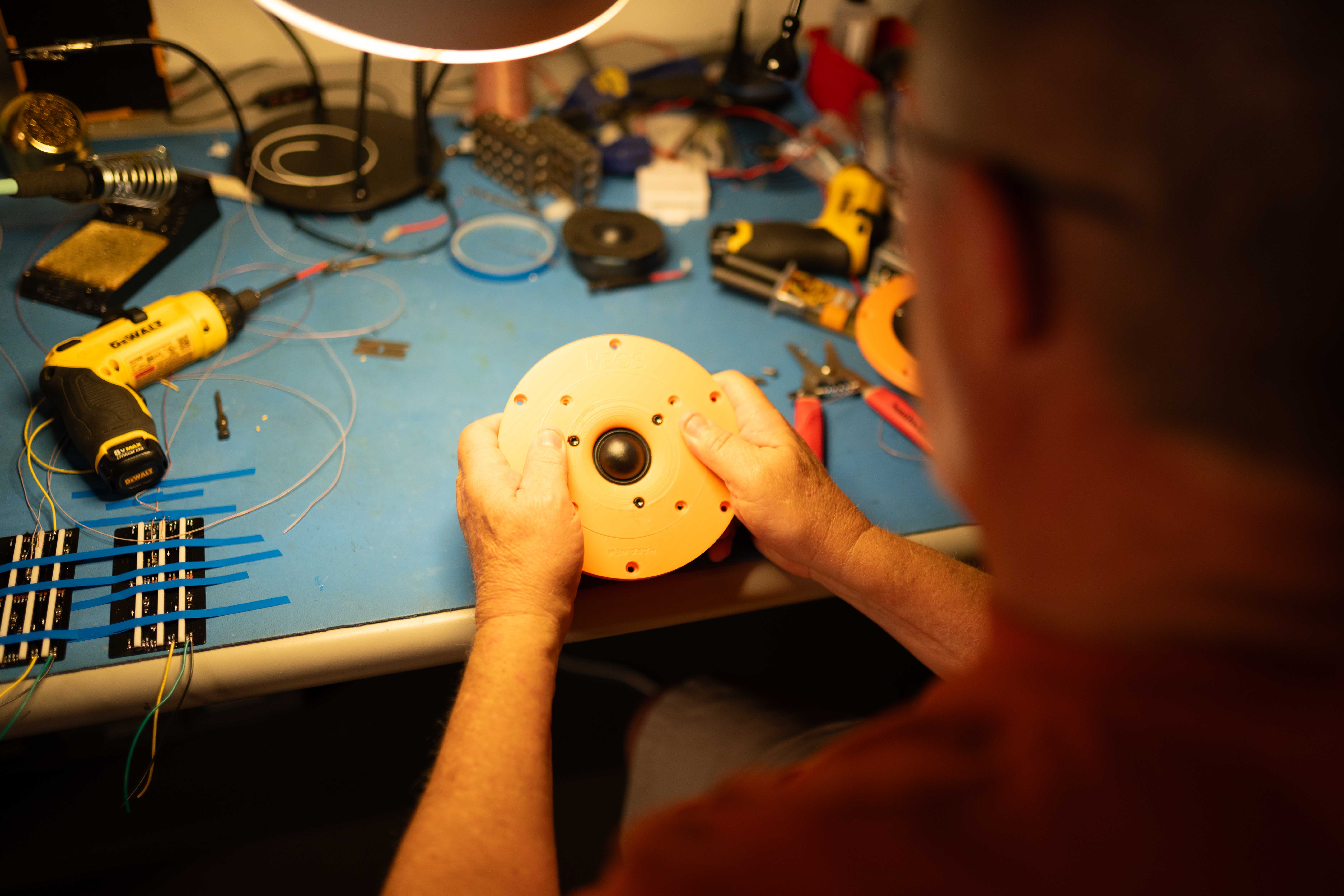 Soen engineer working at a desk with a 3D CAD exploded view of a speaker assembly on a large monitor and an engineering simulation software on a laptop