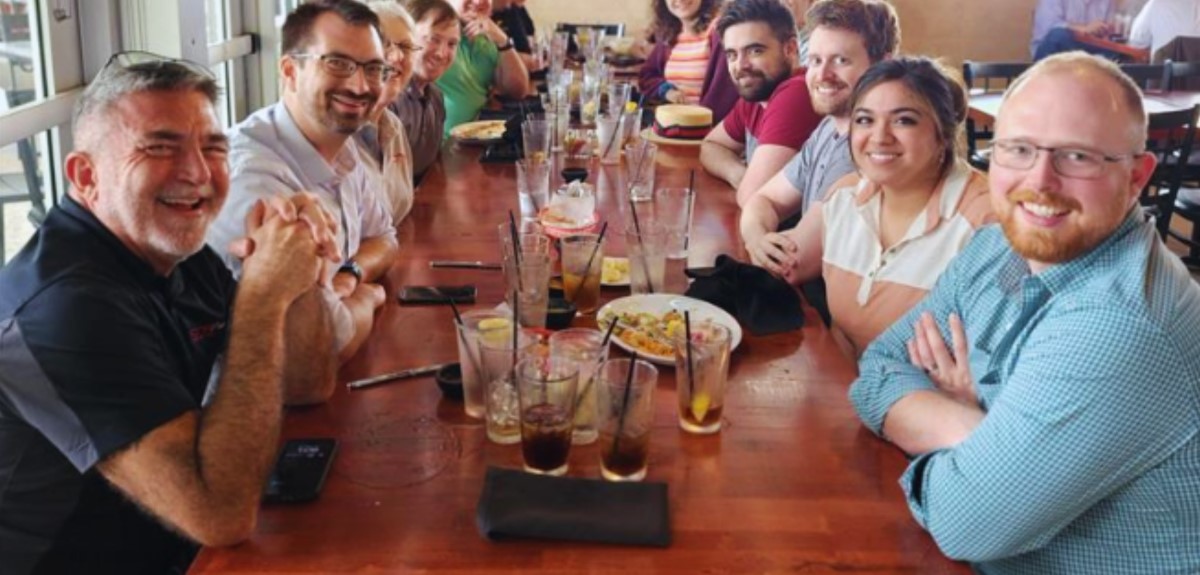 CNF employees gathered at table enjoying lunch and drinks together