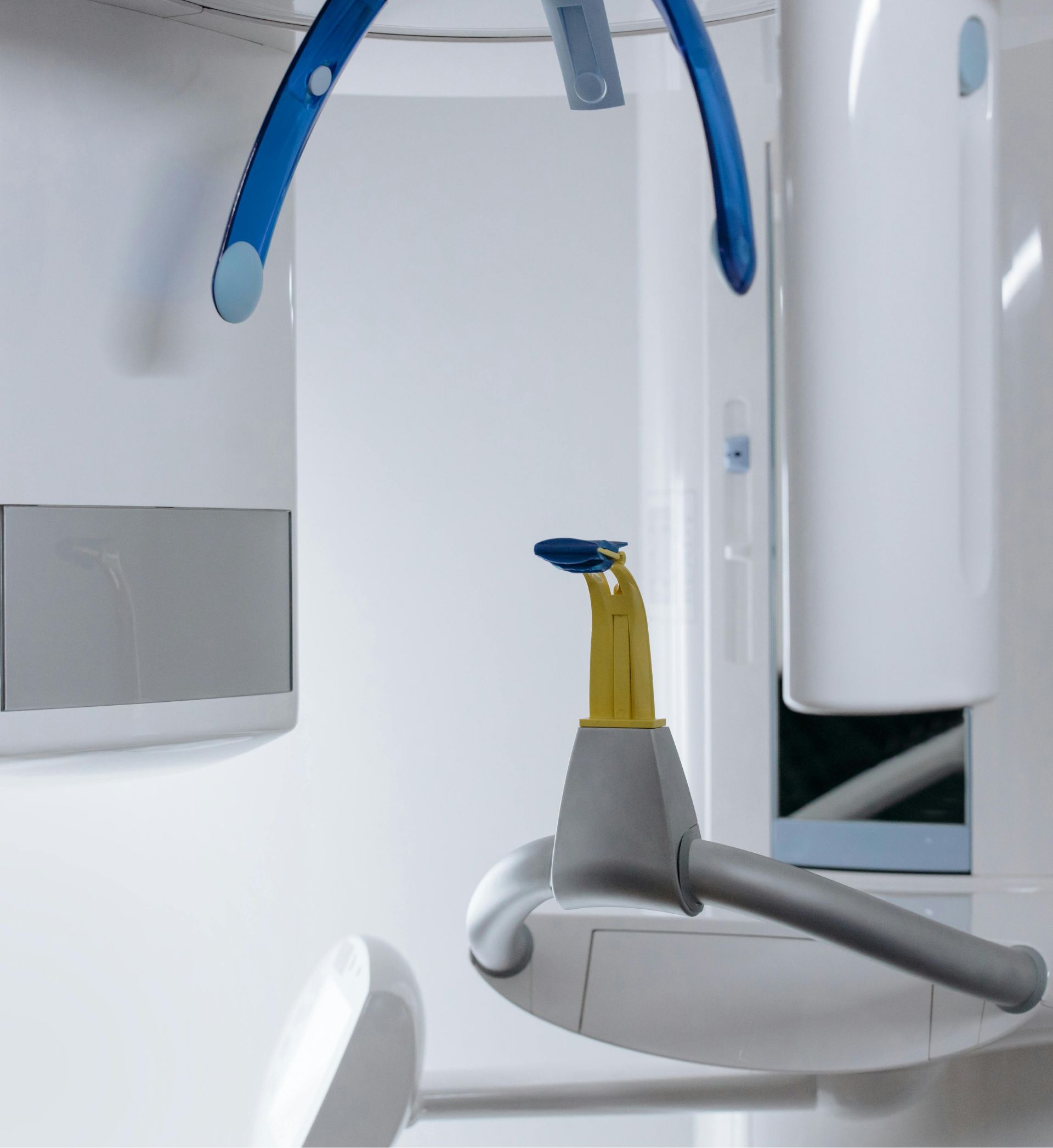 Close-up of a dental X-ray machine inside a dental clinic with blue and yellow components.