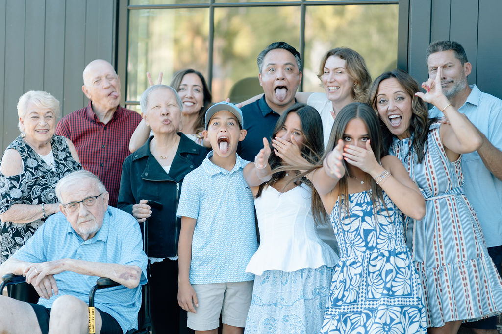 Group of diverse family members making funny faces and gestures outside a building.