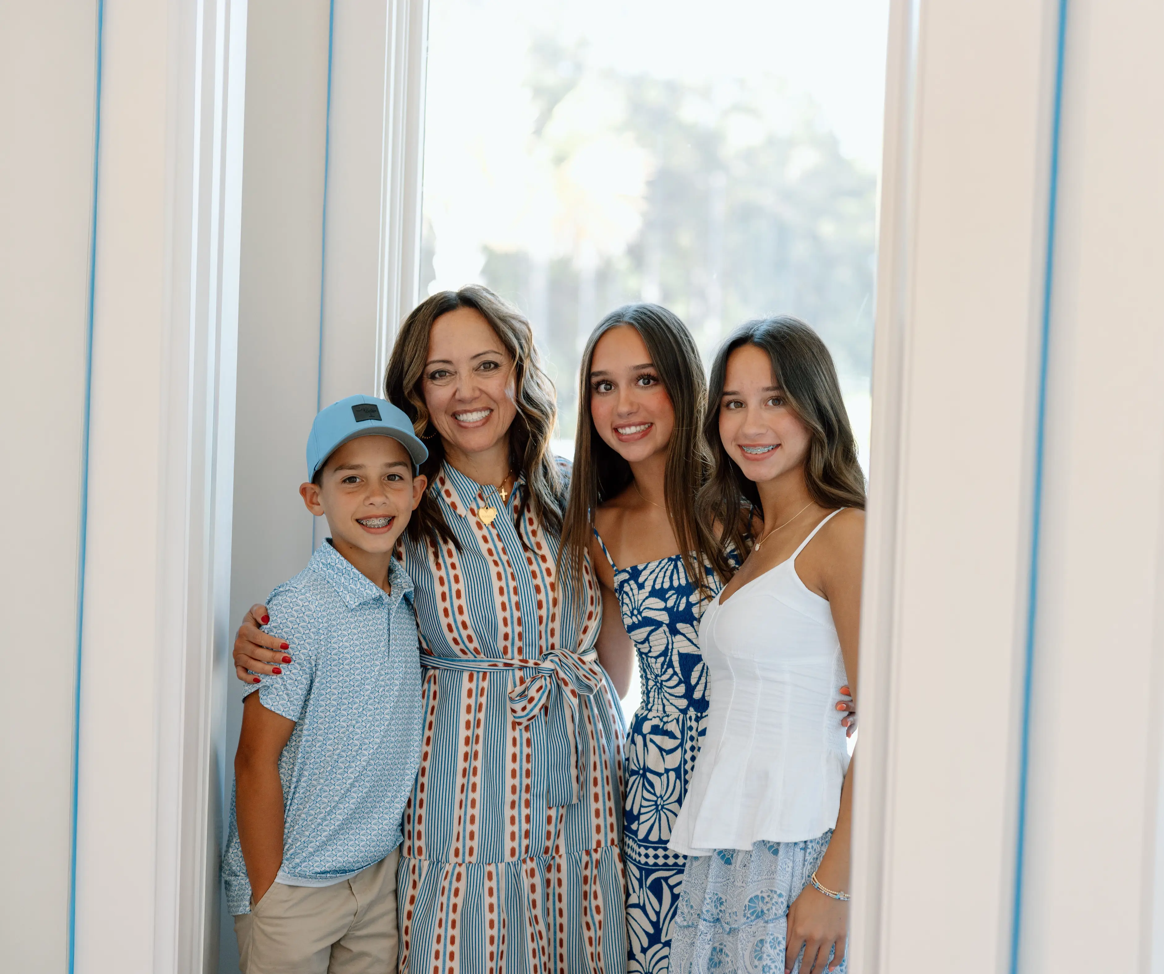 Woman and three children posing together in a bright white hallway
