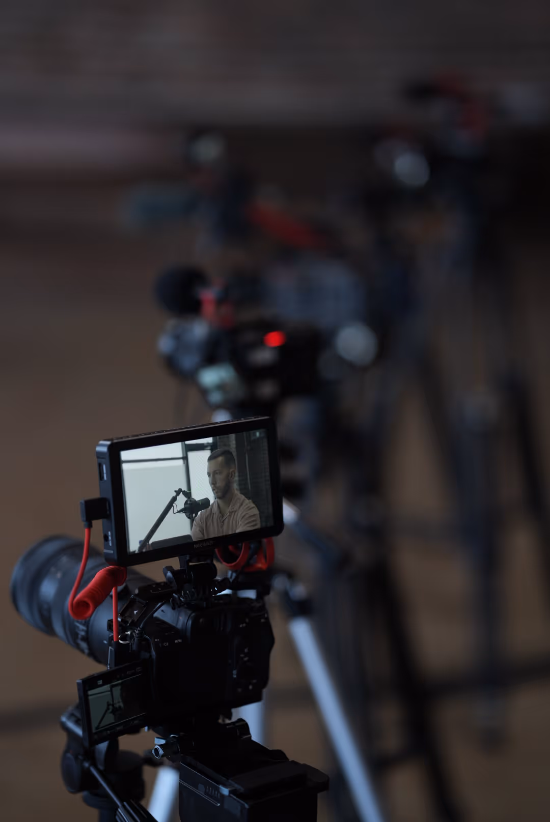 Video camera screen showing a man speaking into a microphone during recording.