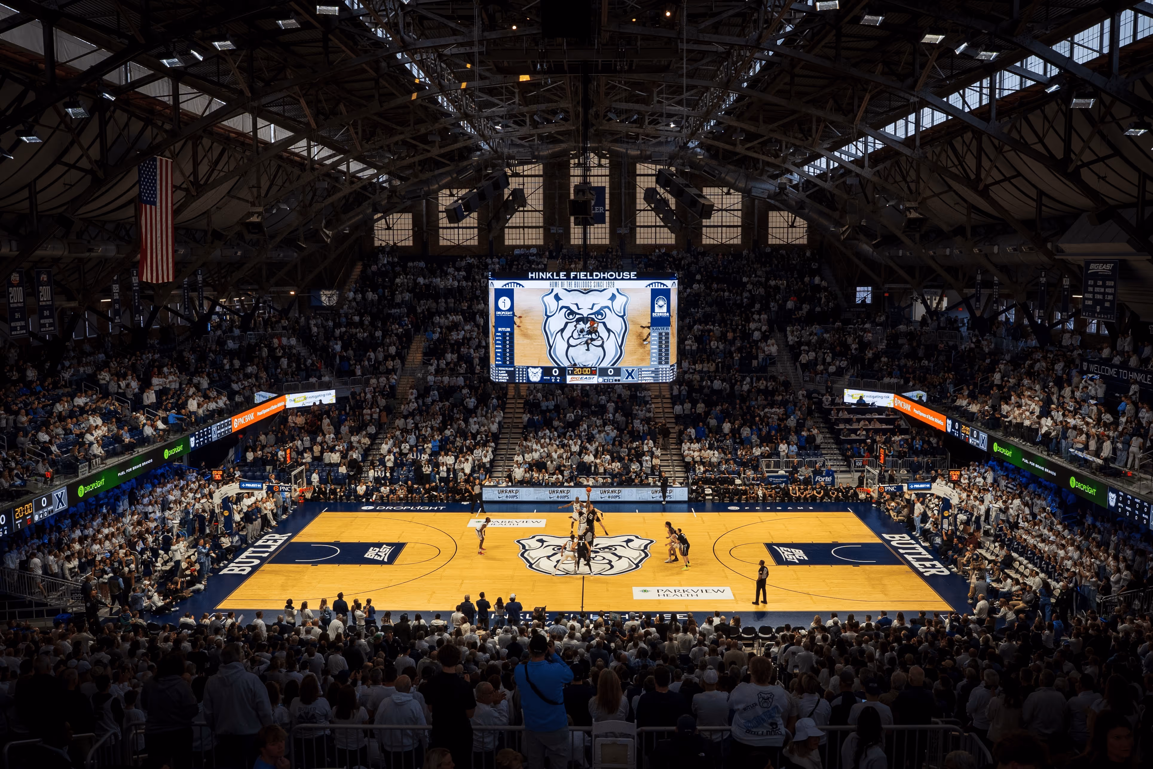 Packed Hinkle Fieldhouse hosting a Butler basketball game with tip-off underway on the court.