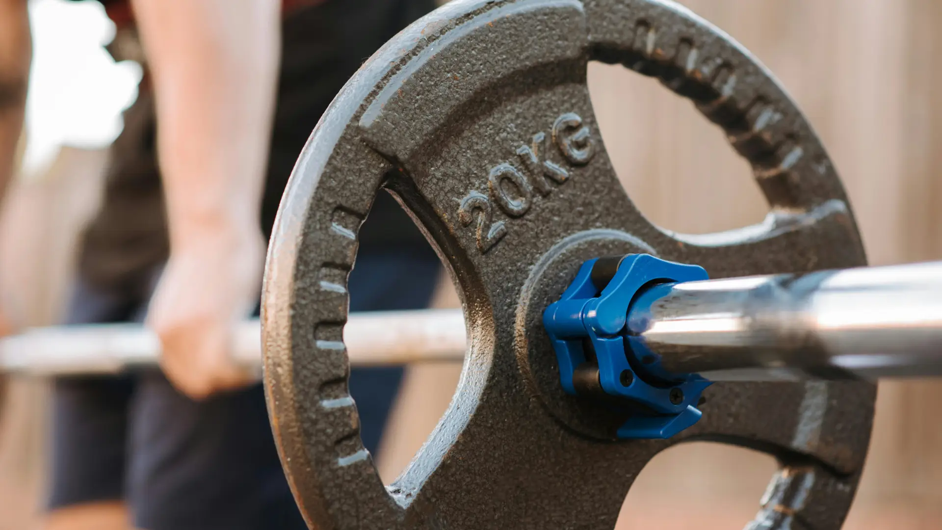 A person lifts a barbell with a blue handle, showcasing strength and focus during a weightlifting session.