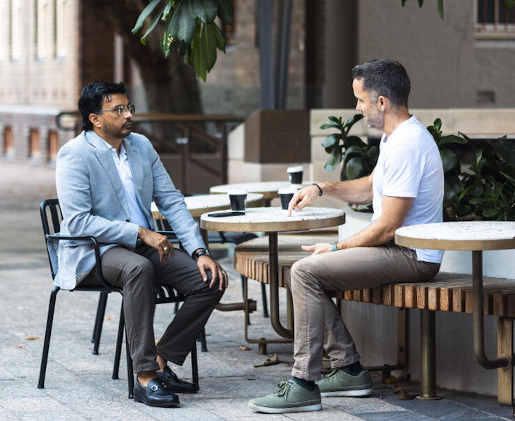 Two men discussing business over coffee at an outdoor café