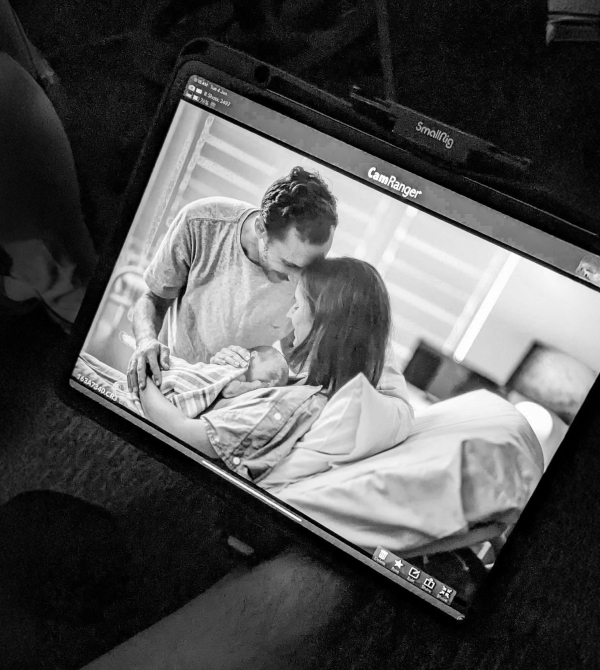 Photo on a SmallRig screen shows a couple lovingly holding a newborn baby in a hospital bed.