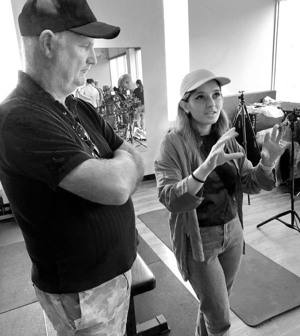 Man listens attentively to a woman explaining with hand gestures in a studio setting with equipment.