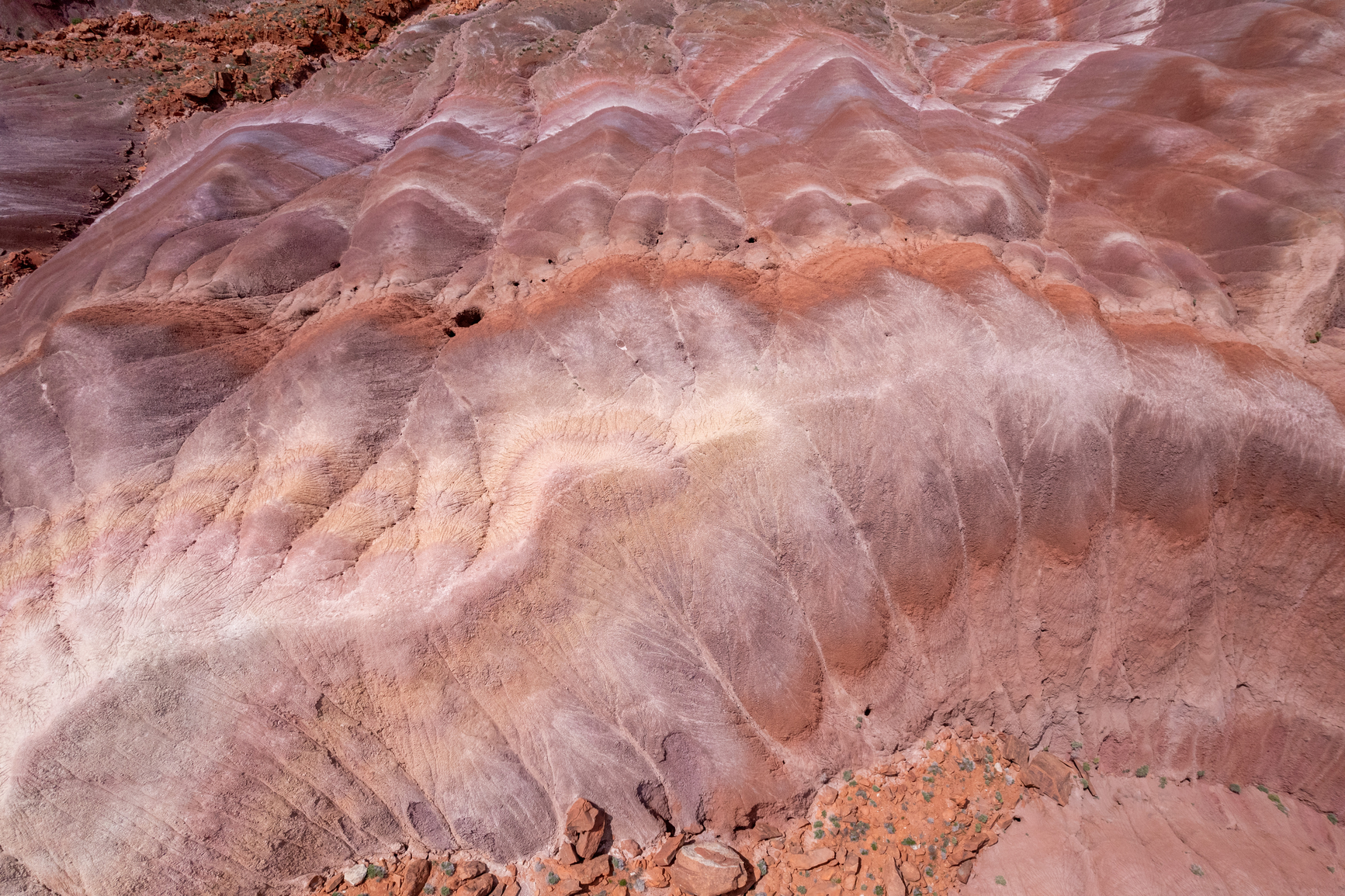 Close-up of multicolored layered rock formations with wavy patterns in shades of red, purple, and beige.